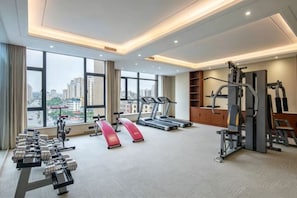 A gym with treadmills, weight machines, and dumbbells.