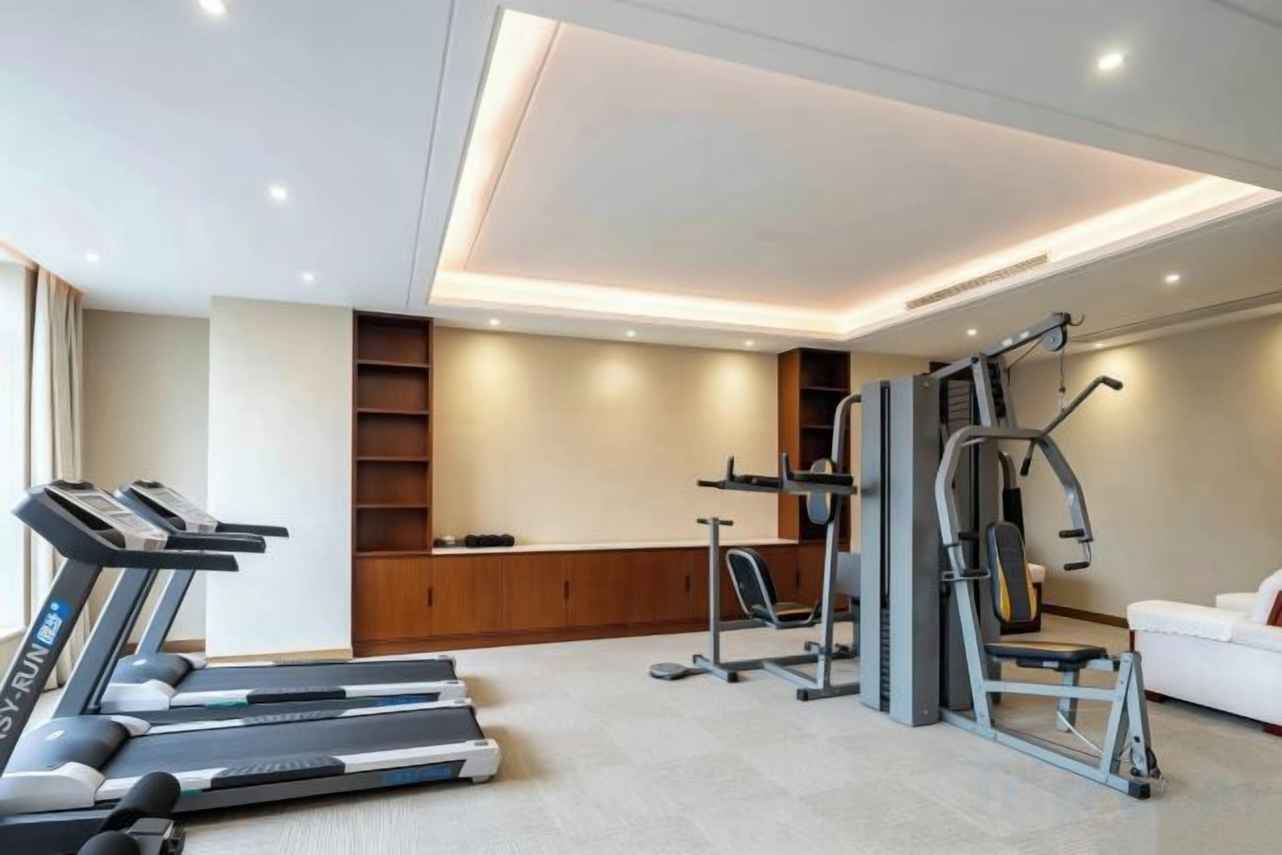 A home gym with treadmills, a stationary bike, and a weight machine.