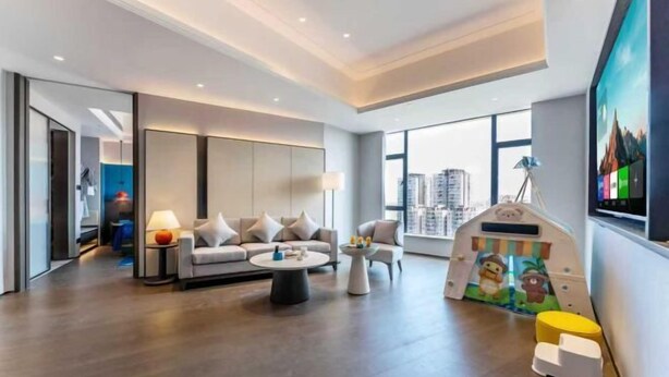 A modern living room with a sofa, coffee table, and a children's play area. - Rufu Hotel (Ganzhou)