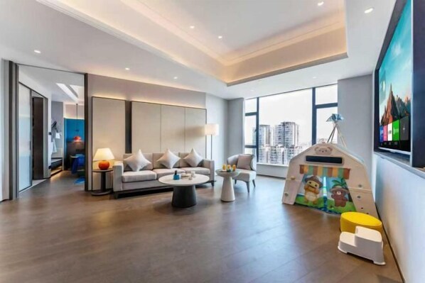 A modern living room with a sofa, coffee table, and a children's play area. - Rufu Hotel (Ganzhou)