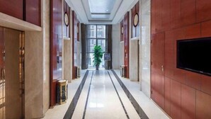 A hotel corridor with a polished floor, wooden paneling, and a large flat-screen TV on the right wall. - Rufu Hotel (Ganzhou)