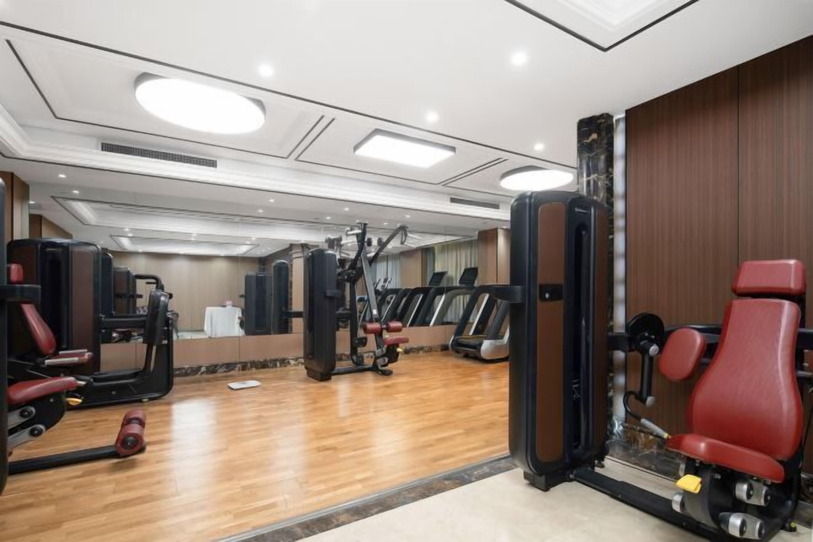 Un gimnasio con equipamiento de ejercicio, una cinta de correr y un espejo.