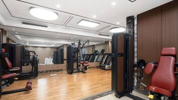 Un gimnasio con equipamiento de ejercicio, una cinta de correr y un espejo.