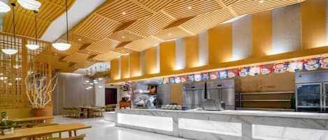 A modern restaurant interior with a high ceiling, wooden slats, and a marble counter.