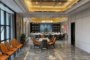 Un salón de conferencias con una larga mesa, varias sillas y un candelabro.