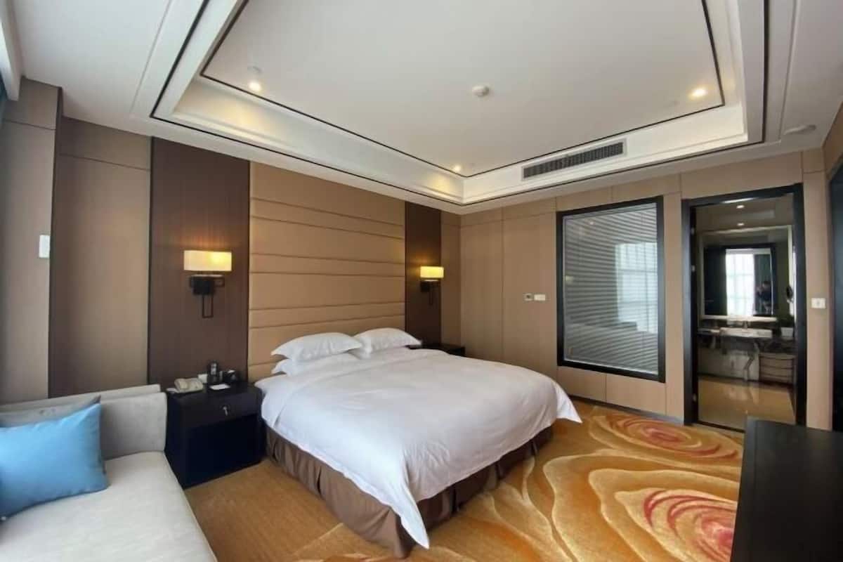 Ein Hotelzimmer mit Bett, Sofa, Schreibtisch und Spiegel.