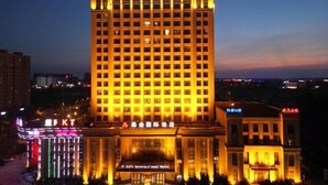 Un hotel de varios pisos con letreros iluminados y una entrada destacada.
