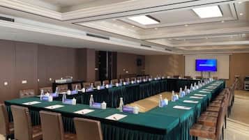 Un salón de conferencias con una larga mesa, tarjetas de identificación y una pantalla de televisión.
