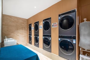 A laundry room with four washing machines and a sink.