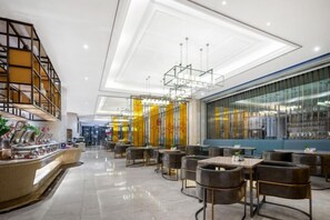 A modern hotel lobby with a bar area, seating arrangements, and a large glass wall.