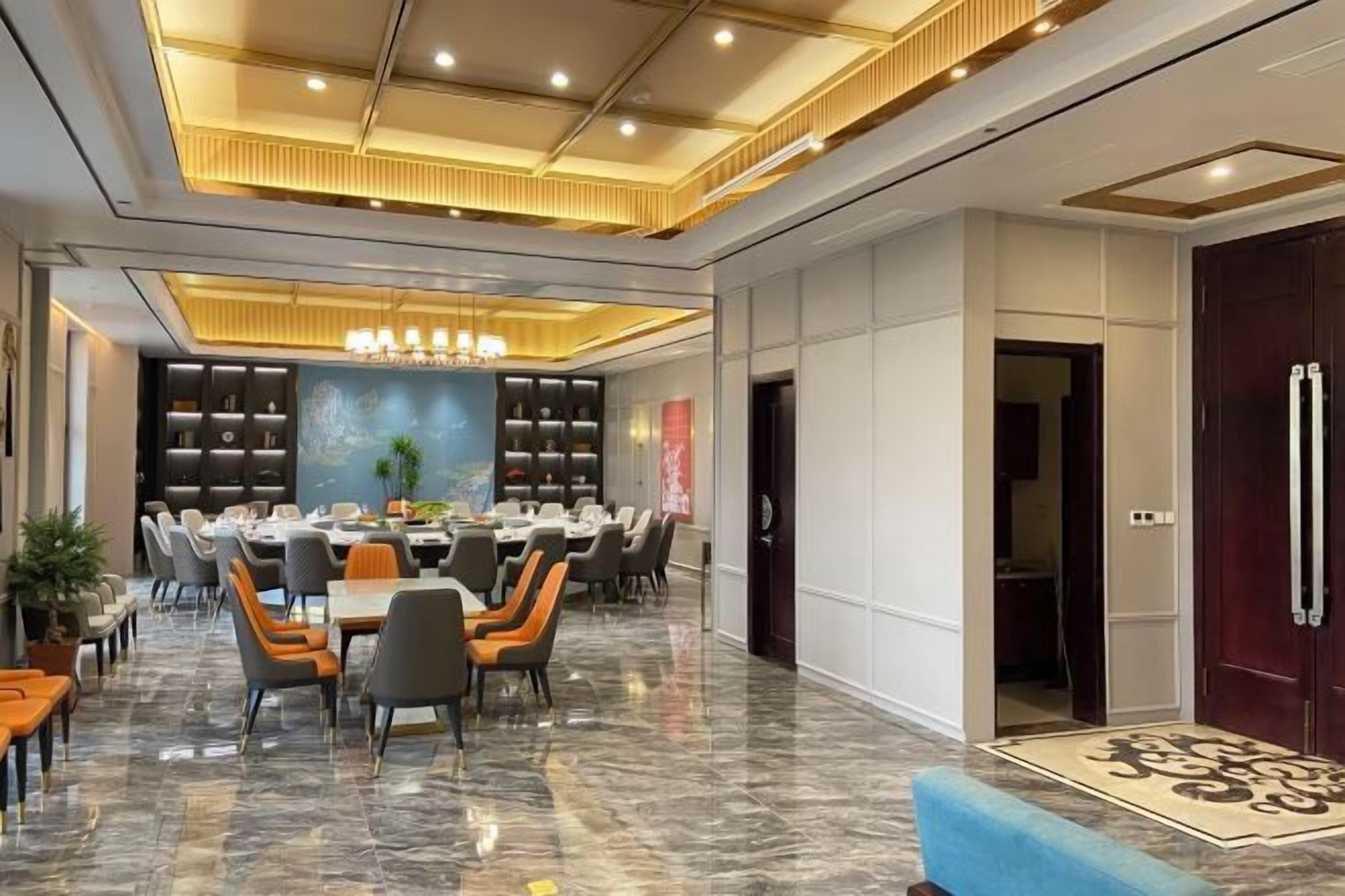 A spacious dining area with a long table, multiple chairs, and a chandelier.