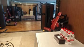 A gym with exercise equipment, a mirror, and bottled water on a table.