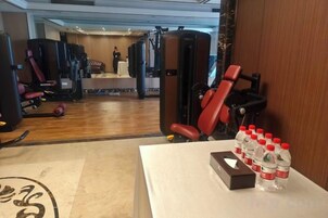 A gym with exercise equipment, a mirror, and bottled water on a table.