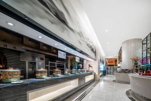 A hotel lobby with a marble reception desk, a large pillar, and a view of the interior.