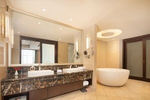 Une salle de bain moderne dotée d’un grand miroir, de deux lavabos, d’une baignoire et d’un meuble-lavabo avec espace de rangement.