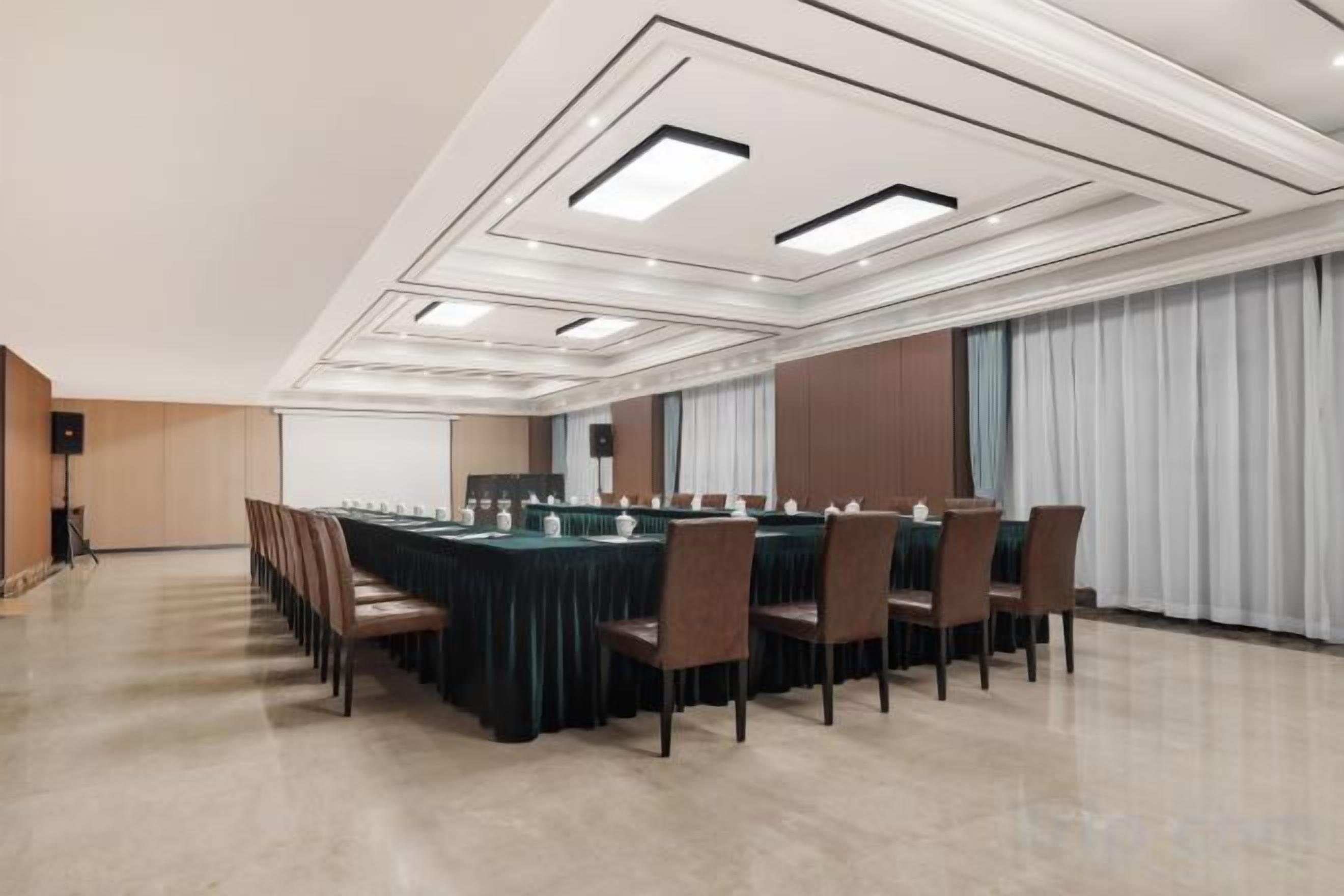 Une salle de conférence équipée d’une longue table, de chaises et d’un écran de projection.