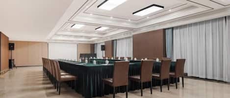 Uma sala de conferências com uma mesa comprida, cadeiras e uma tela de projetor.