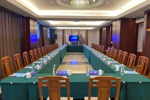 Una sala de conferencias con una mesa larga, sillas y una pantalla de televisión.