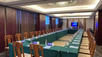 A conference room with a long table, chairs, and a projector screen.