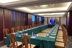 A conference room with a long table, chairs, and a projector screen.