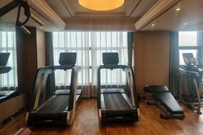 A gym with treadmills, a bench, and a mirror.