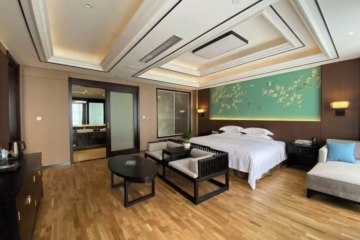 Ein Hotelzimmer mit einem großen Bett, einer Couch, einem kleinen Tisch und einer dekorativen Wand.
