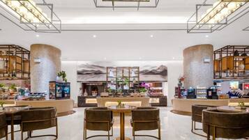 Een moderne hotellobby met een bar in het midden, zitgedeeltes en een decoratieve wand.
