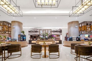 A modern hotel lobby with a central bar area, seating arrangements, and a decorative wall.
