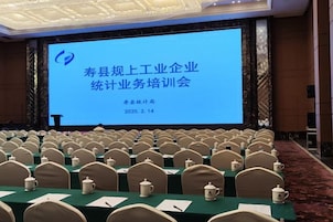 Un salón de conferencias con filas de sillas mirando a una pantalla grande que muestra texto.