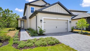 A modern two-story house with a garage, a well-maintained lawn, and a paved driveway. - Inviting Home near Disney with Waterpark & Resort Access at Encore Resort -. (Kissimmee)