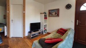 A room with a bed, a TV, a bookshelf, a painting, and a door. - Appartement Dans Maison de Village, au Calme, Entre Annecy et Genève (Villy-le-Pelloux)