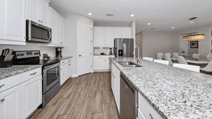 A modern kitchen with white cabinetry, stainless steel appliances, and a granite countertop.