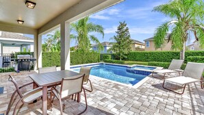 A covered outdoor area with a pool, patio furniture, and a grill. - Glorious Home near Disney: Game Room & Waterpark Access - 660LA (Kissimmee)