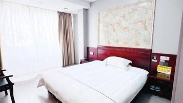 Ett hotellrum med en stor säng, ett skrivbord, en stol, ett nattduksbord och ett konstverk som hänger på väggen.