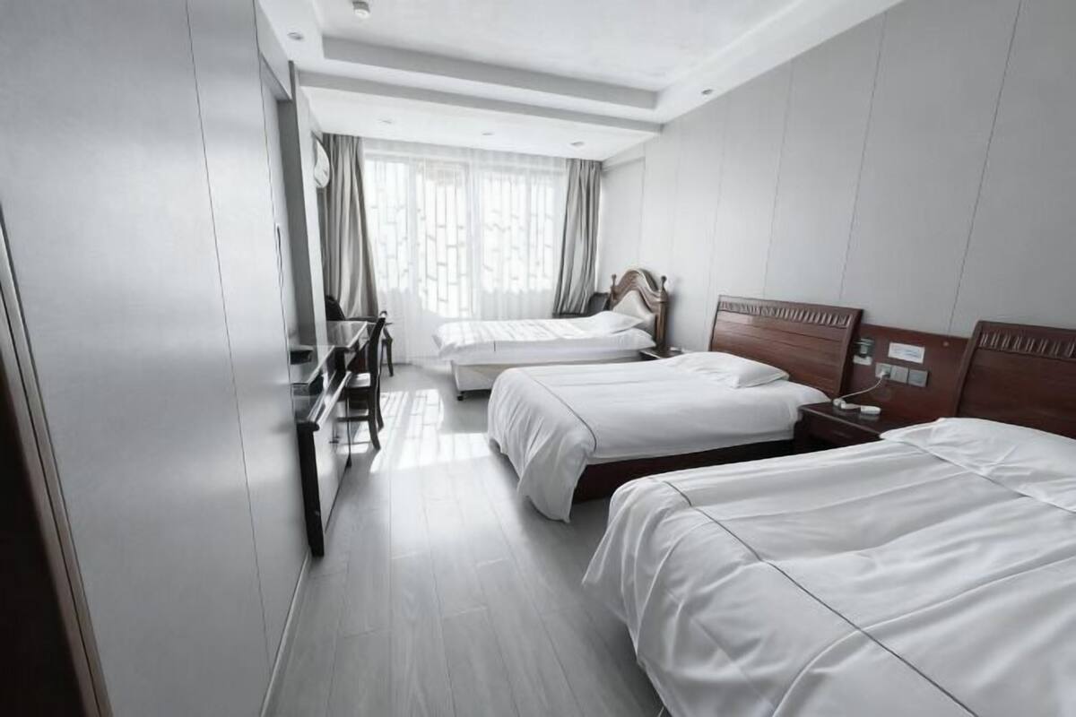 A hotel room with two beds, a desk, and a chair.