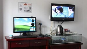Um quarto com uma escrivaninha, monitor de computador, televisão e um aquário.