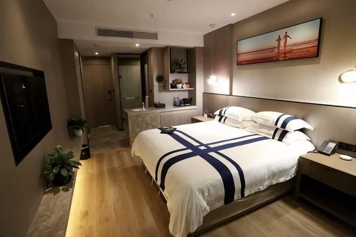 Une chambre d’hôtel moderne avec un grand lit, une table de chevet et un téléviseur.