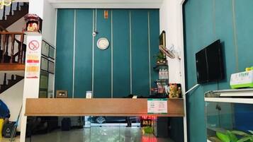 A reception area with a teal wall, a clock, a reception desk, and a staircase.