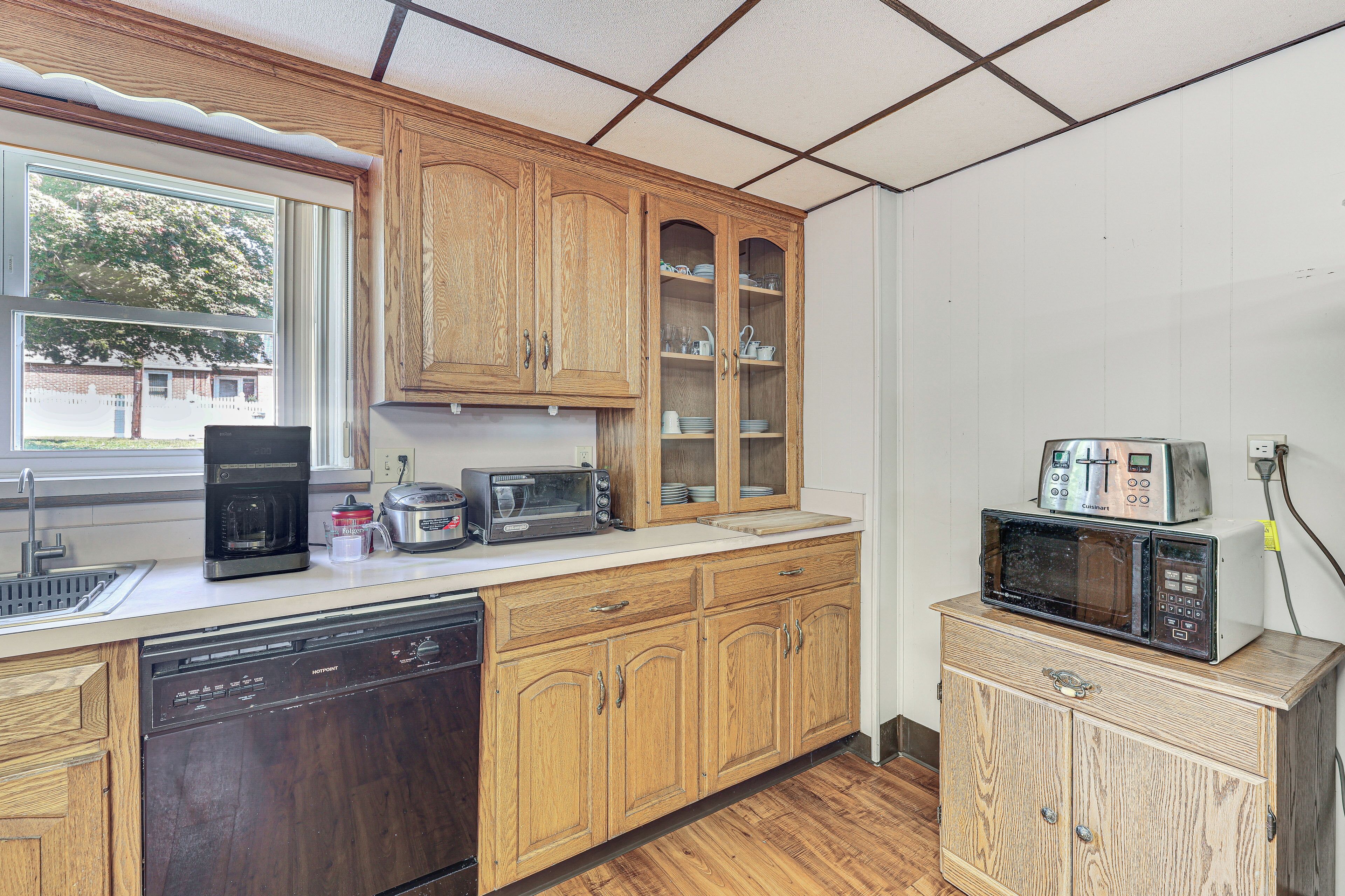 A kitchen with wooden cabinets, a dishwasher, a coffee maker, a toaster, and a microwave.
