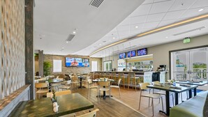 En modern restaurang med flera sittområden, en bar och en tv-skärm där sportevenemang visas.