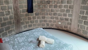Ein Zimmer mit Ziegelwand, einem an der Wand befestigten Flachbildfernseher und einem Bett mit einem blumengemusterten Matratze sowie einem aufgerollten weißen Handtuch.