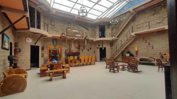 Eine geräumige Lobby mit hoher Decke, Holzmöbeln und einer Treppe zu einer oberen Ebene.