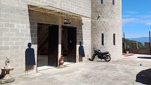 Ein historisches Gebäude mit großem Eingangsbereich, ein Motorrad vor der Tür und freier Blick auf die umliegende Landschaft.