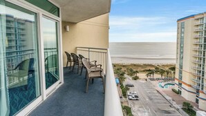 Un balcone con vista sulla spiaggia e un'area di parcheggio.