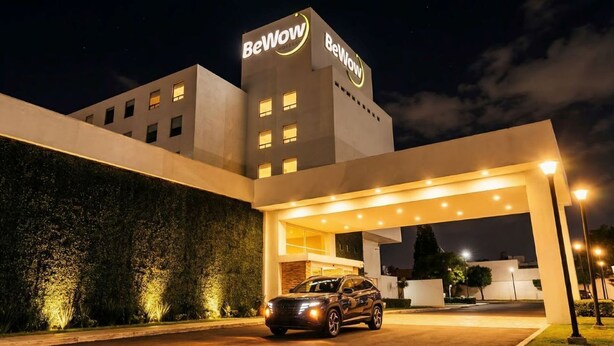 A modern hotel with a prominent 'BeWow' sign, a covered entrance, and a parked car. - BeWow Hotel Querétaro (Querétaro)