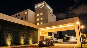 A modern hotel with a prominent 'BeWow' sign, a covered entrance, and a parked car. - BeWow Hotel Querétaro (Querétaro)