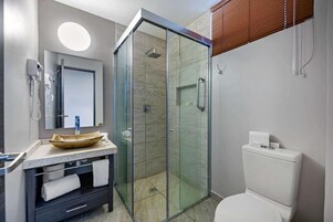 Un baño moderno con ducha envuelta en vidrio, inodoro y tocador con lavabo.