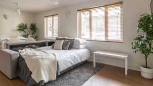 Ein modernes Schlafzimmer mit Bett, Nachttischen, einer Bank und einer Topfpflanze.