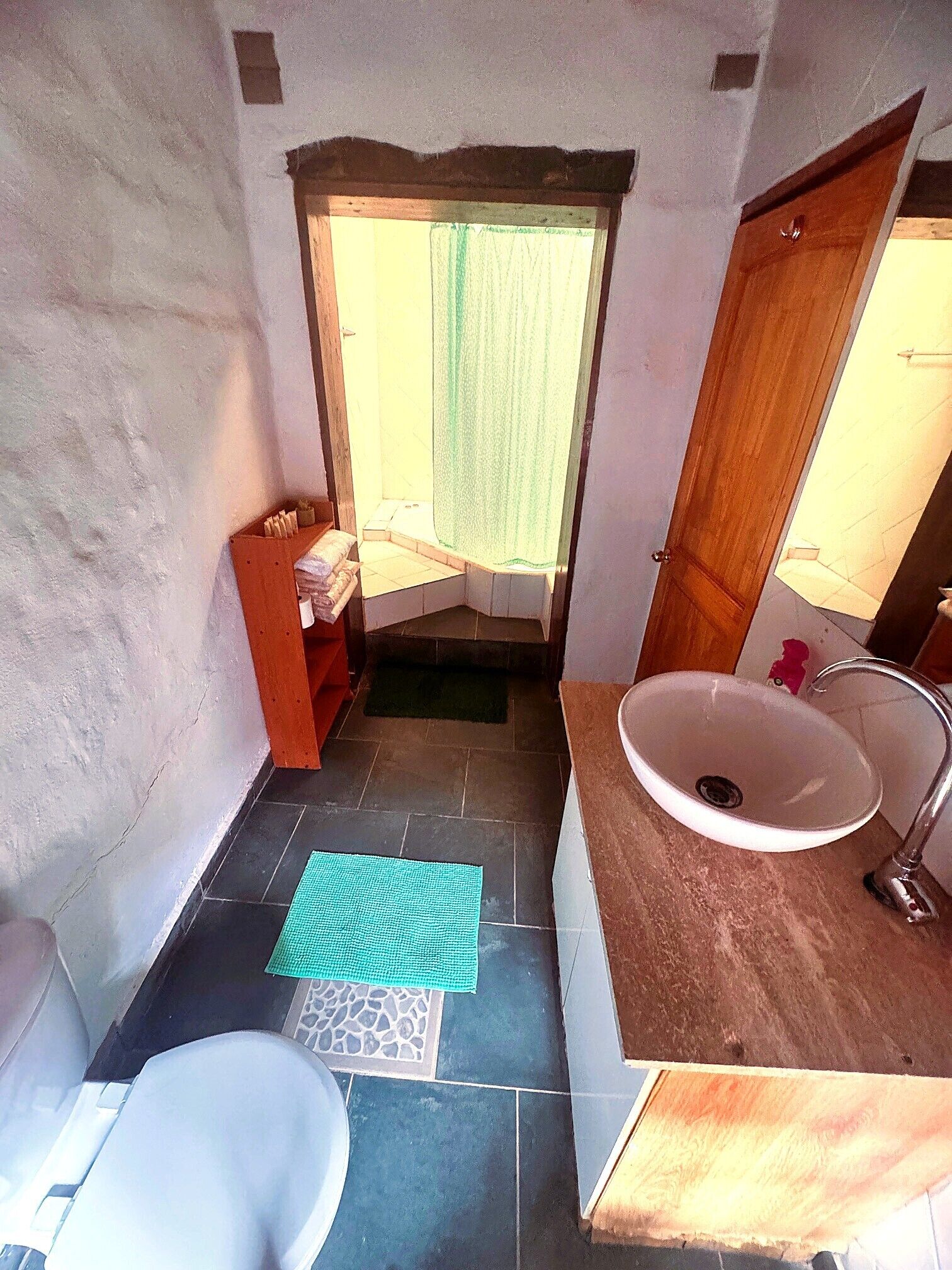 Un baño con lavamanos blanco, un espejo, ducha e inodoro.