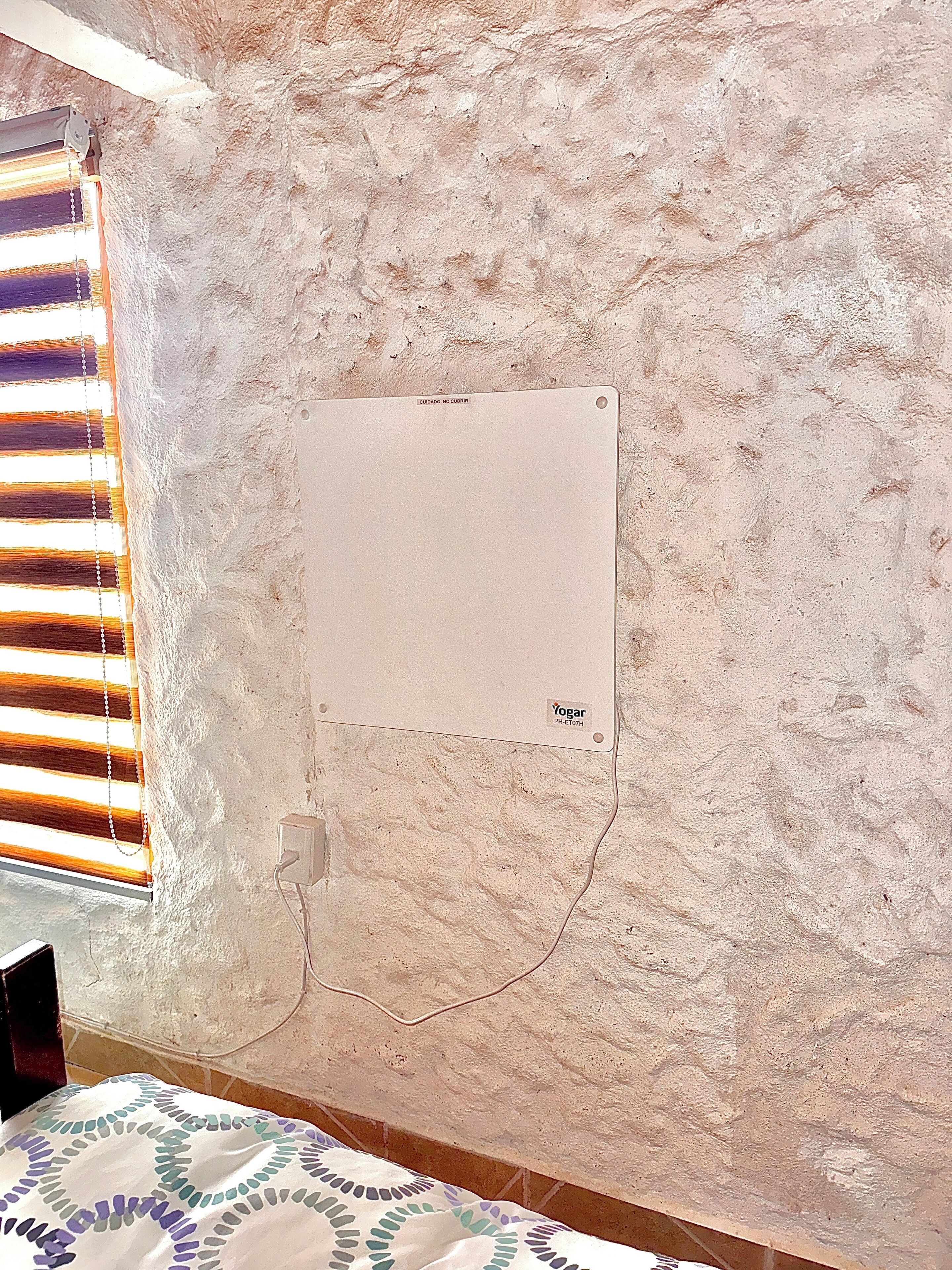 Une pièce avec un mur à texture, une prise de courant et un tableau blanc.